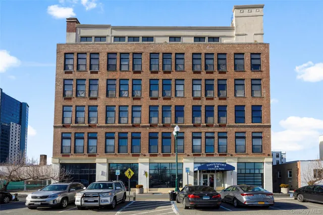 a front view of a building with lot of cars and trees