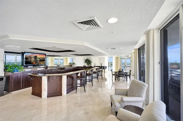 a living room with stainless steel appliances kitchen island granite countertop a table chairs and a view of living room
