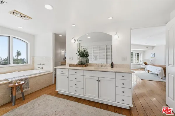 a spacious bathroom with a granite countertop sink mirror and bathtub