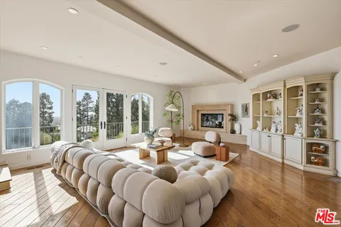 a living room with furniture large windows and wooden floor
