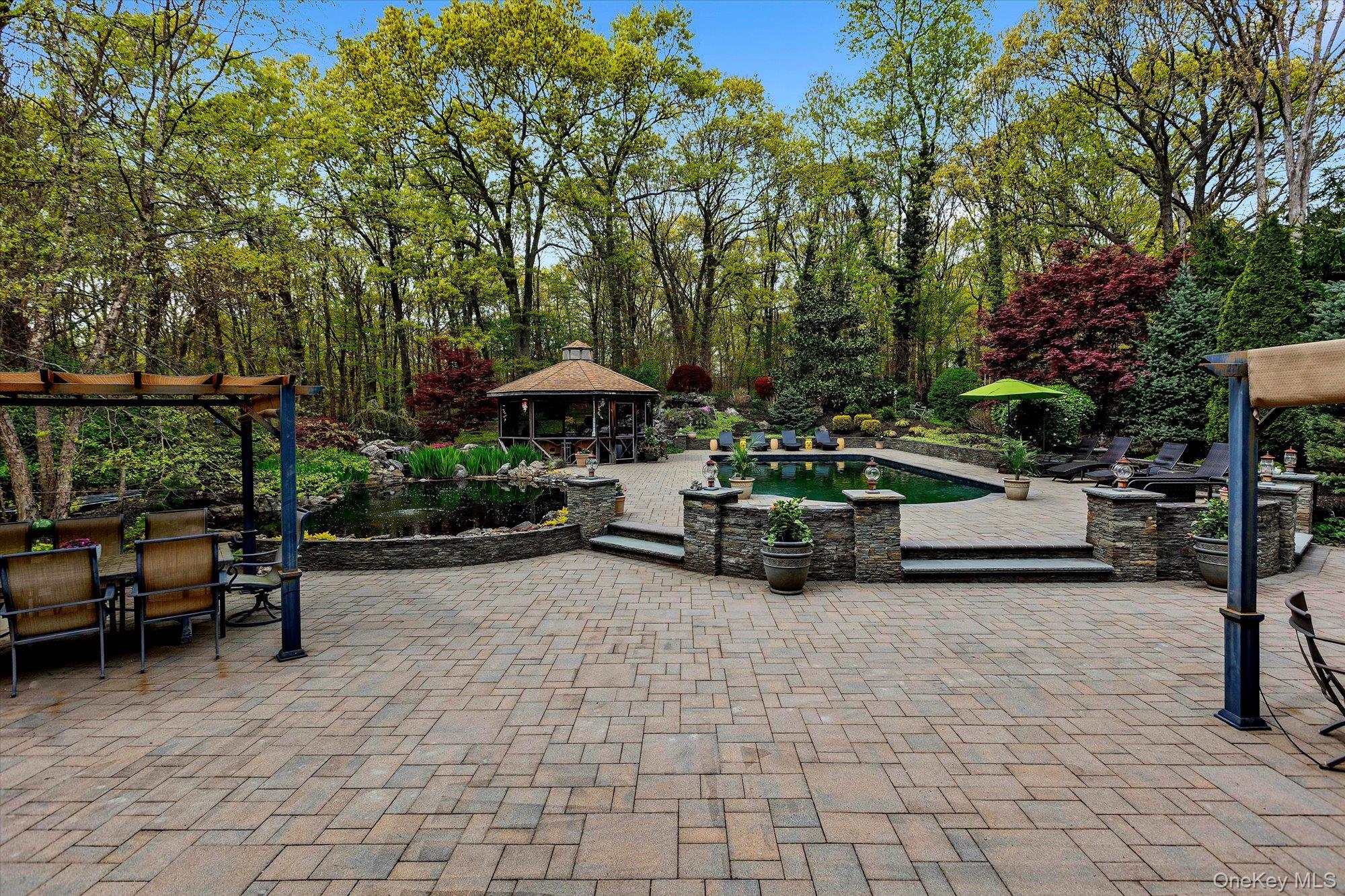 263 Old Commack Road Kings Park, NY 11754 - Photo 23 of 42 a view of a patio with table and chairs under an umbrella with large trees