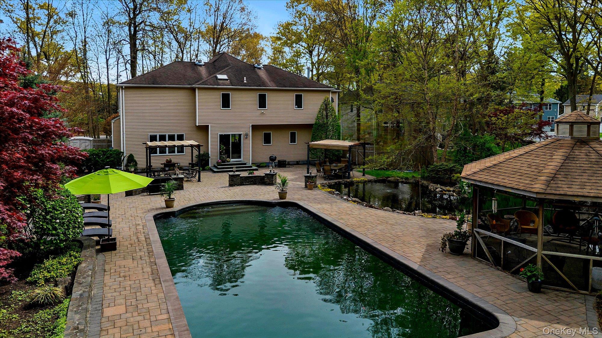 263 Old Commack Road Kings Park, NY 11754 - Photo 41 of 42 a view of a house with pool and chairs under an umbrella