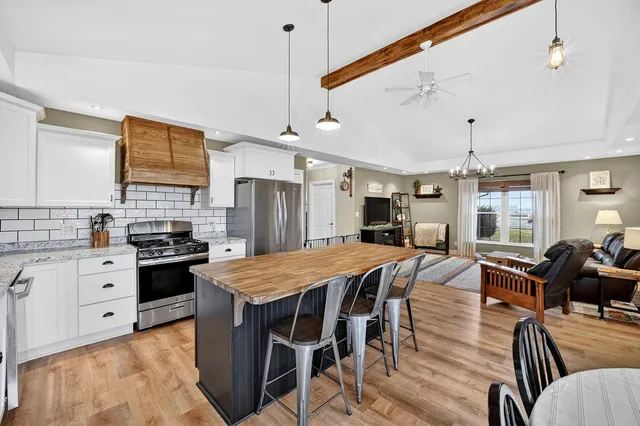 a kitchen with granite countertop a stove a sink a dining table and chairs with wooden floor