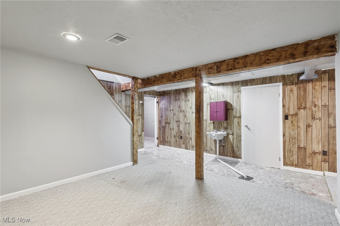 611 Wilson Street Struthers, OH 44471 - Photo 39 of 44 Finished below grade area with carpet floors, wooden walls, stairs, and a textured ceiling