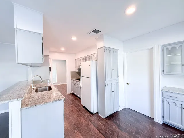 a kitchen with granite countertop wooden floors a stove and a refrigerator