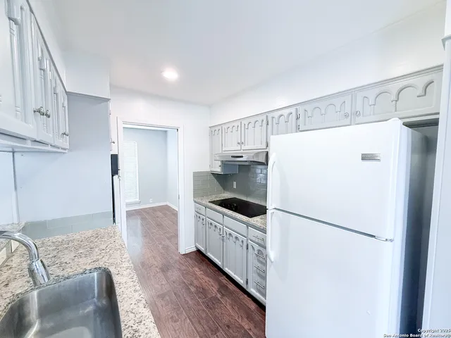 a kitchen with granite countertop a refrigerator and a sink