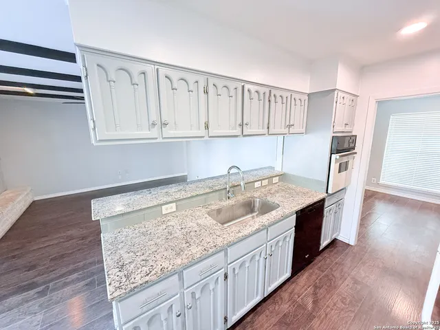 a kitchen with granite countertop a sink stove and cabinets