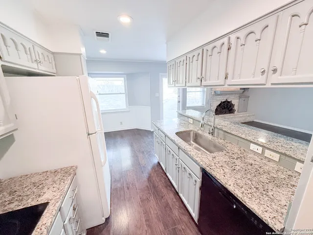 a kitchen with granite countertop a sink a stove and refrigerator