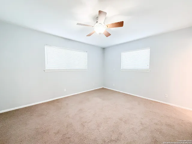 an empty room with a window and a fan
