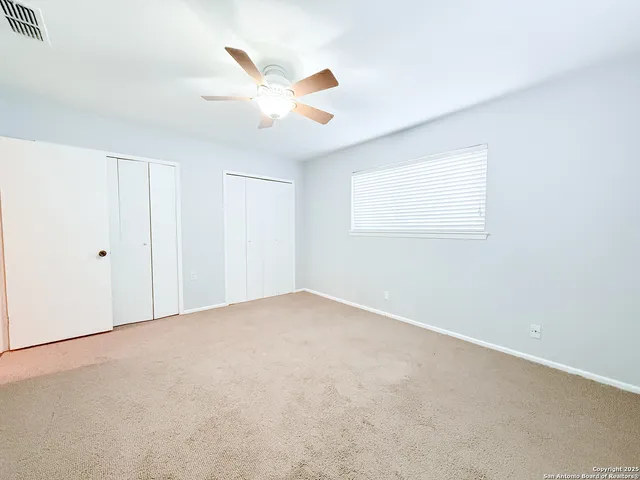 an empty room with windows and fan