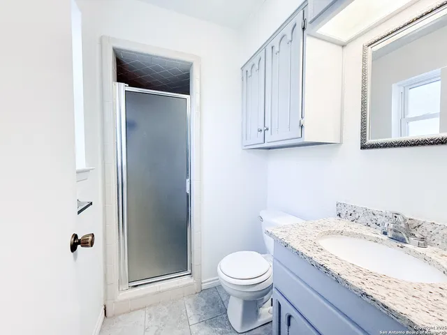 a bathroom with a granite countertop sink and a toilet