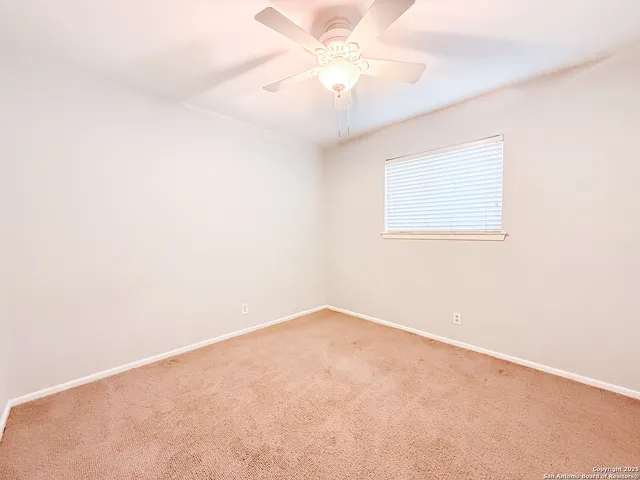an empty room with a window and a fan
