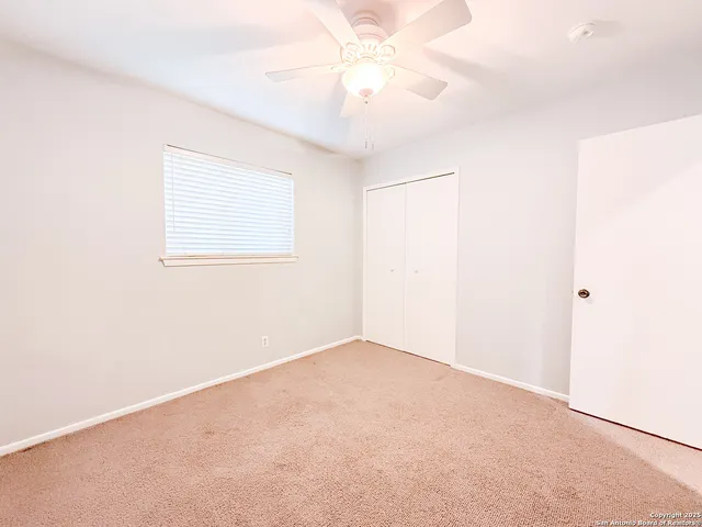 an empty room with a window and a fan