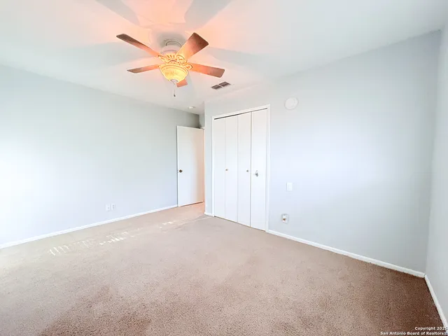 an empty room with a ceiling fan and window