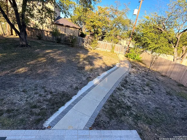 a view of a yard with wooden fence