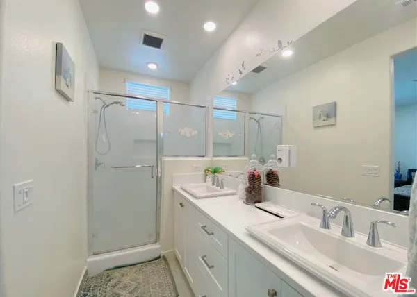 a bathroom with a double vanity sink mirror and shower
