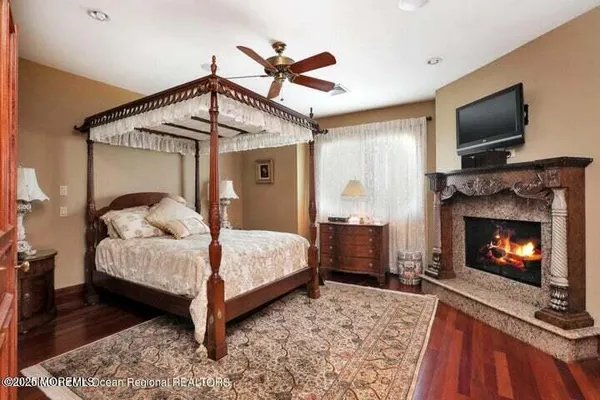 a bedroom with a bed a flat screen tv and a fireplace
