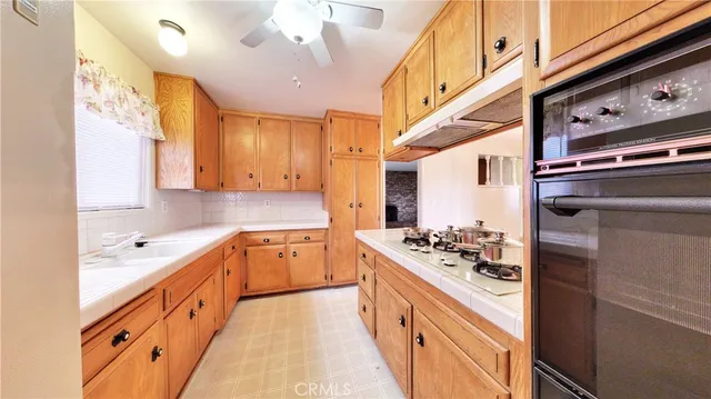 a white kitchen with stainless steel appliances granite countertop a stove and a sink