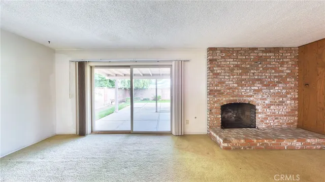 a view of an empty room with a fireplace and a window
