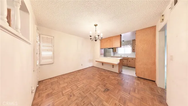 a view of a livingroom with a fireplace a chandelier and entryway