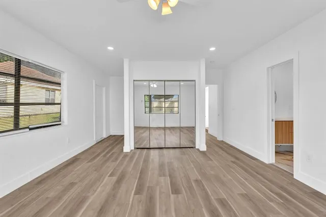 an empty room with wooden floor and windows