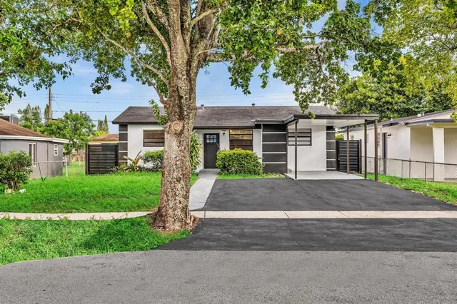 a front view of a house with a garden and tree