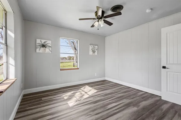 a view of empty room with wooden floor and fan