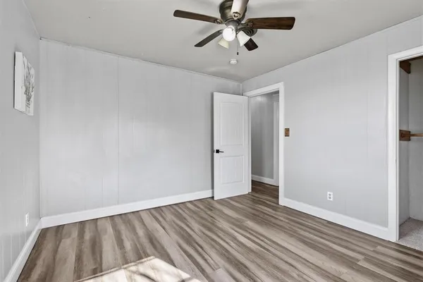 a view of empty room with wooden floor and fan
