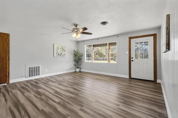 a view of an empty room with a window and wooden floor