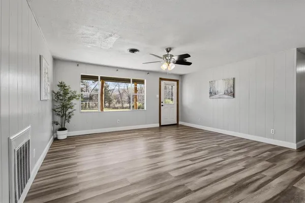 a view of an empty room with a window and wooden floor