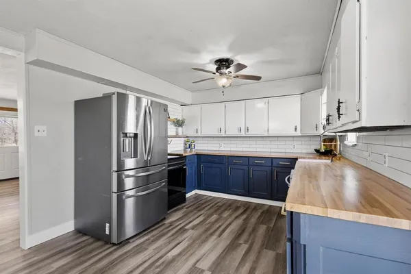a view of a kitchen with a refrigerator a ceiling fan and wooden floor