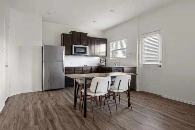 a kitchen with a table chairs refrigerator and microwave