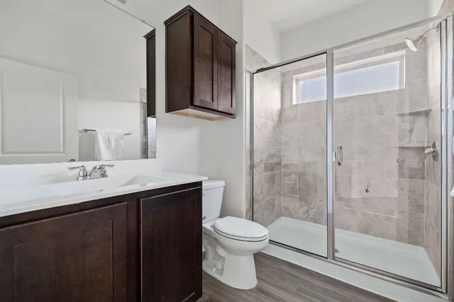 a bathroom with a shower sink vanity mirror and toilet