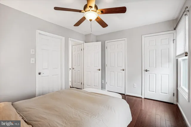 a view of a bedroom with wooden floor and a ceiling fan