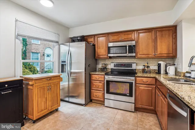 a kitchen with stainless steel appliances granite countertop a refrigerator stove and sink