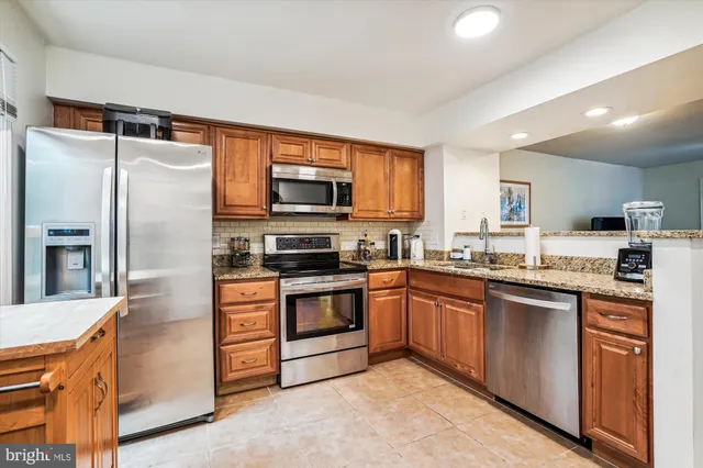 a kitchen with stainless steel appliances granite countertop a refrigerator a stove top oven a sink and dishwasher