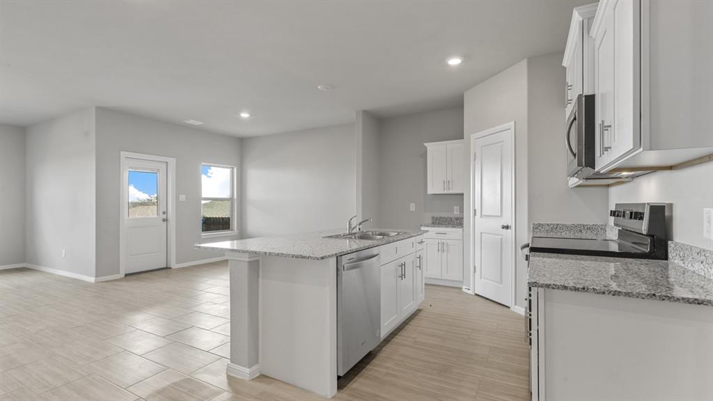 16421 Rangerville Drive Justin, TX 76247 - Photo 4 of 40 a kitchen with stainless steel appliances granite countertop a stove a sink and a refrigerator