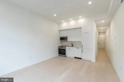 a large kitchen with a large counter top a sink stainless steel appliances and cabinets