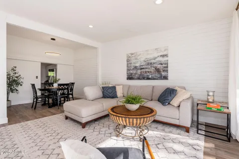 a living room with furniture and a dining table with wooden floor