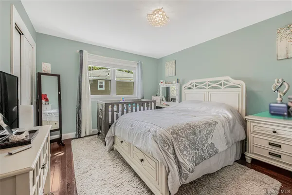a bedroom with a bed a mirror on dresser and a large window
