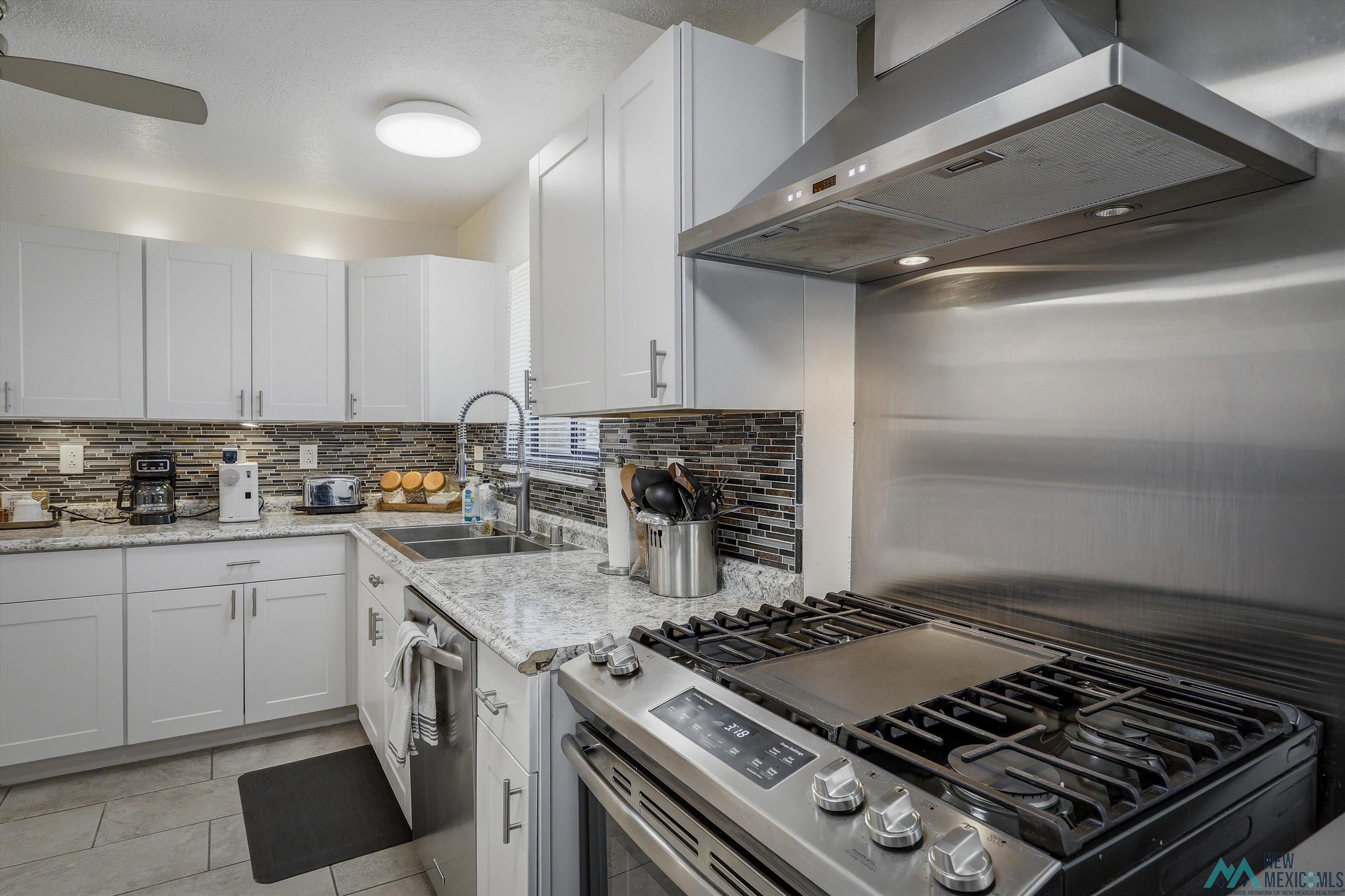 83 Juniper Road Chama, NM 87520 - Photo 13 of 56 Modern kitchen featuring white shaker cabinetry, stainless steel appliances, granite countertops, and a mosaic tile backsplash