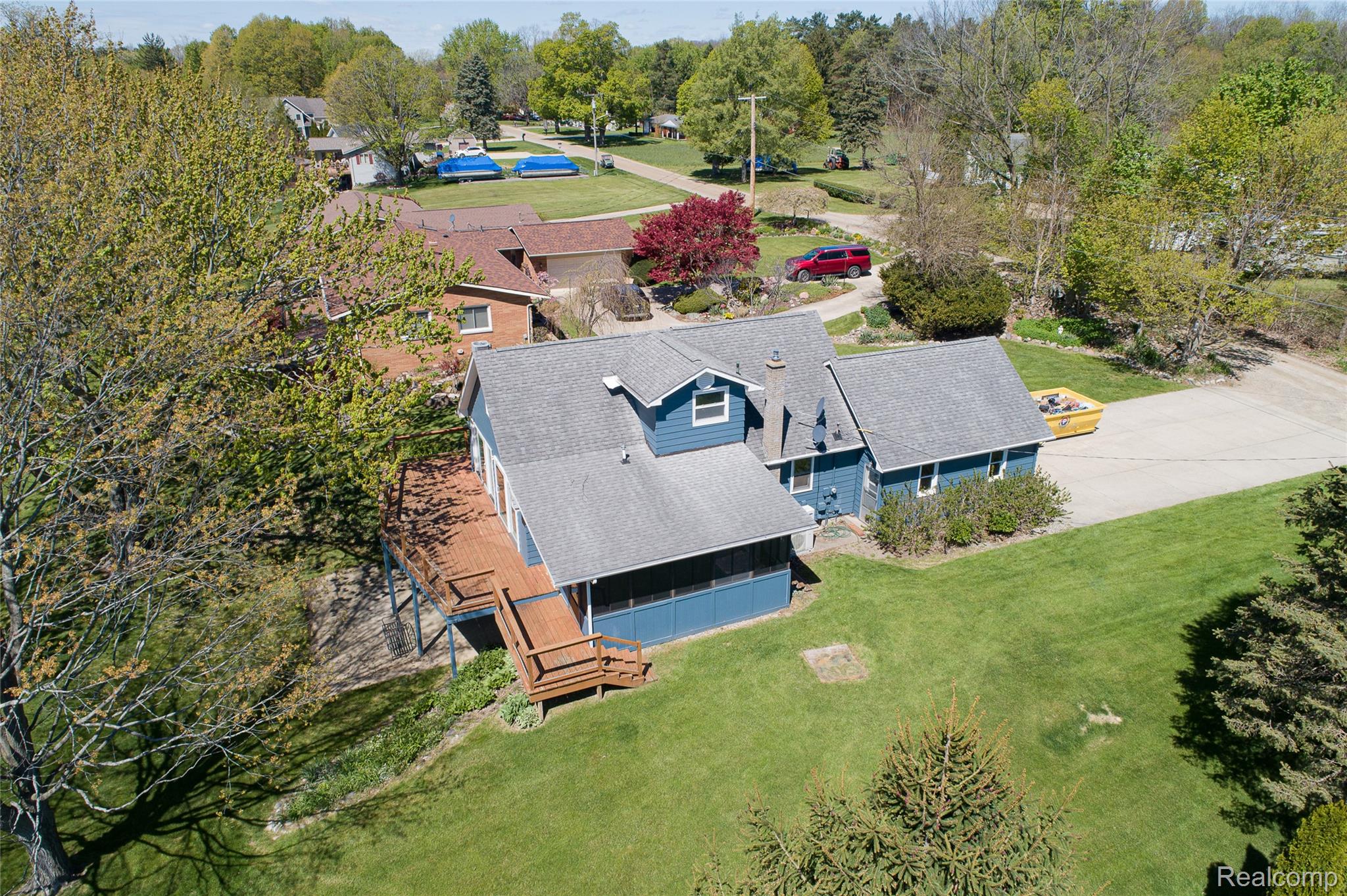 2855 Farmers Creek Road Metamora, MI 48455 - Photo 44 of 51 Blue siding residence featuring a multi-level wood deck, a screened porch, and a gravel driveway