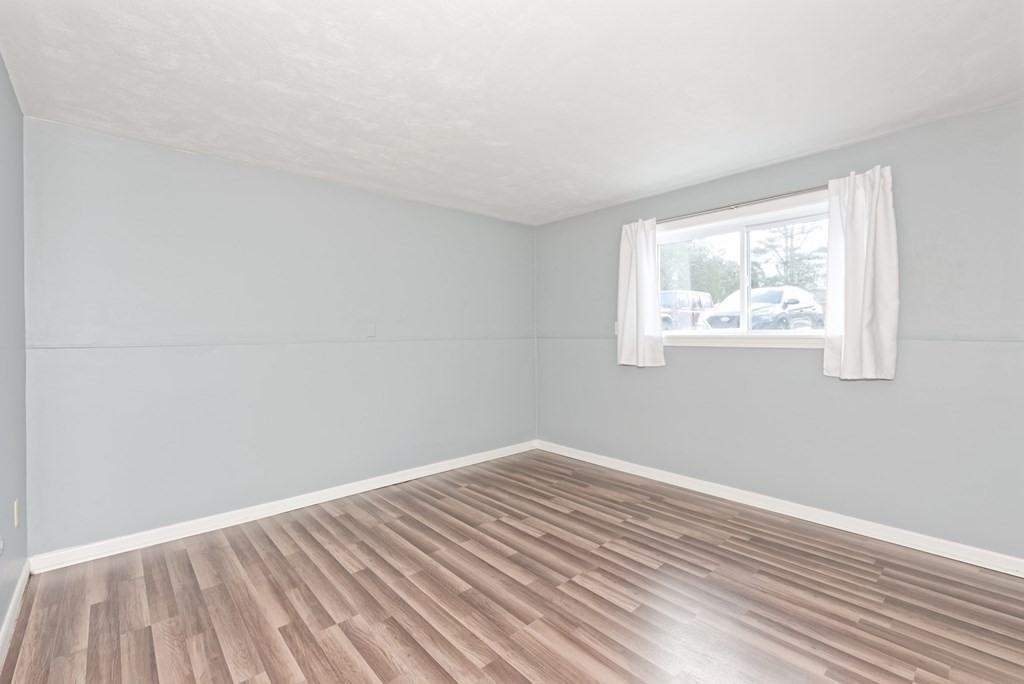176 Maple Avenue, Unit 27 Rutland, MA 01543 - Photo 6 of 19 an empty room with wooden floor and windows