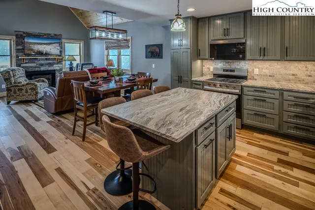 a kitchen with stainless steel appliances kitchen island granite countertop a stove top oven a sink dishwasher a dining table and chairs with wooden floor