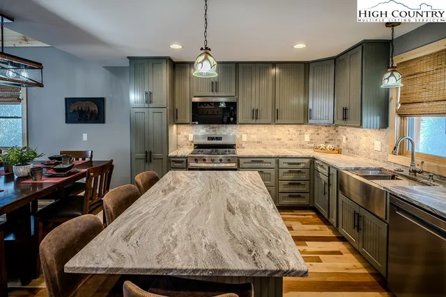 a kitchen with stainless steel appliances granite countertop a stove a sink a microwave a refrigerator and chairs