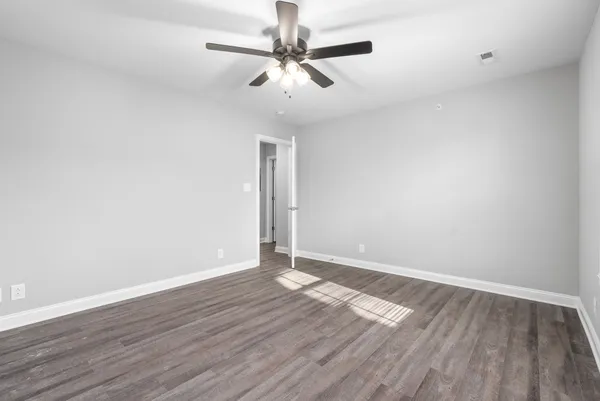 an empty room with wooden floor and ceiling fan