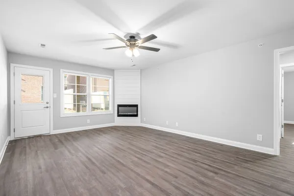an empty room with wooden floor fan and windows