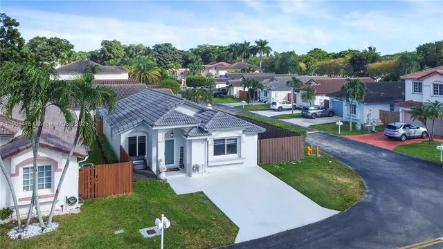 a view of a house with a big yard plants and large tree