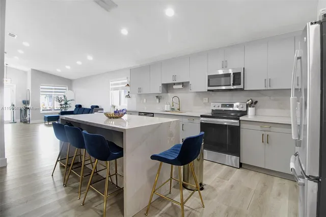 a kitchen with stainless steel appliances kitchen island granite countertop a sink a stove a dining table and chairs