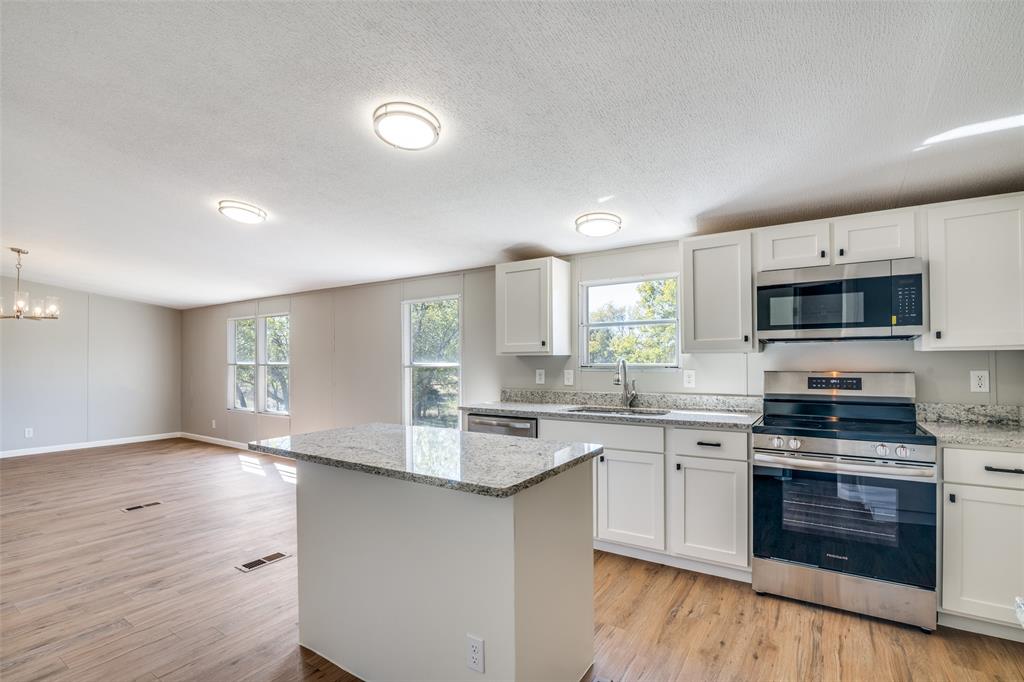 3176 North Ridge Crandall, TX 75114 - Photo 11 of 24 a kitchen with stainless steel appliances granite countertop a stove top oven a sink dishwasher and a microwave oven with wooden floor